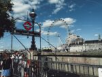 Entrance to the Westminster tube station with the London Eye visible in the background under a blue sky