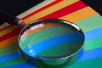 Magnifying glass resting on surface with stripes of different colours