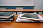 Books and a tablet sitting on a table in a classroom